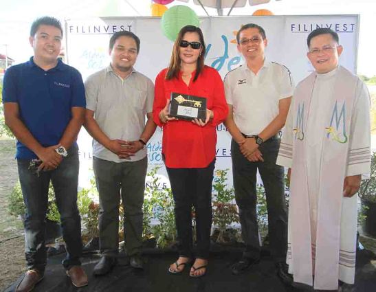 Turnover. Homeowner Nimfa Tampus (center) receives the symbolic key on behalf of her neighbors for their homes at Phase 6 at Aldea del Sol that developer Filinvest Land, Inc. has completed. She is flanked by (from left) subdivision administrator Marc Menina, project development manager Archie M. Igot, area general manager Allan Go Alfon and Fr. Raffy de Gracia, who blessed the new village.